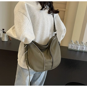 Detail view of khaki nylon crossbody bag showing metal zippers and adjustable wide strap