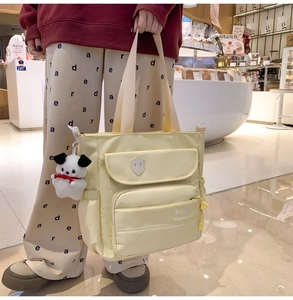 Dettaglio della borsa tote in nylon giallo chiaro con tasche e ciondolo a cucciolo