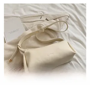 Detail showing the cream white faux leather bag with LUKADE embossed logo on textured fabric