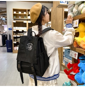 Detail of black nylon backpack featuring white Happy graphic and alien illustration on flap