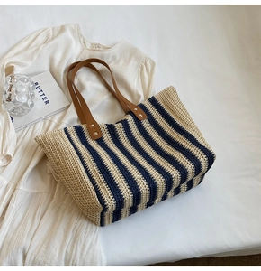 Détail d'un grand sac cabas tissé avec rayures bleu marine et anses en cuir marron