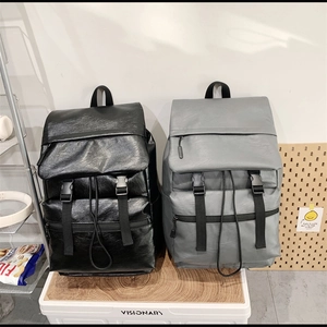 Detail view of minimalist PU leather backpacks in black and grey with buckle closure