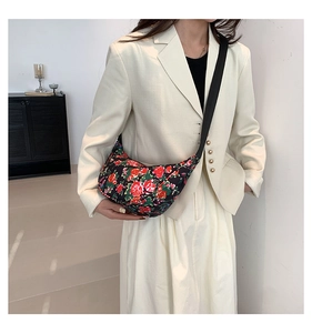 Detail of floral crossbody chest bag in black with vibrant red and green flower patterns