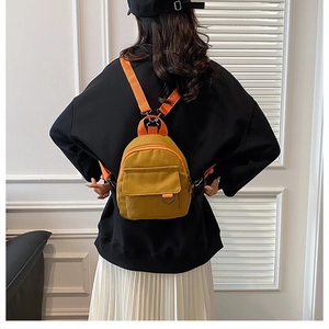 Détail du mini sac à dos en toile jaune moutarde avec bretelles orange sur modèle