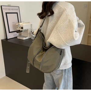 Model wearing army green nylon crescent crossbody bag with silver zippers and wide strap