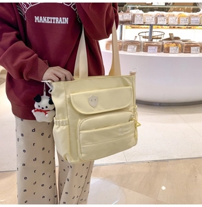 Dettaglio della borsa tote in nylon giallo chiaro con multitasche e ciondolo a forma di cane