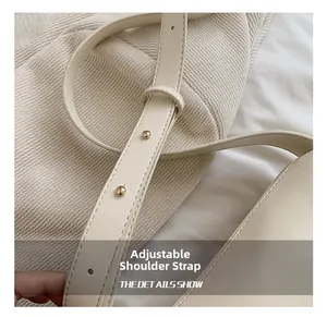 Detail of adjustable shoulder strap on cream PU leather bag with gold metal buckles