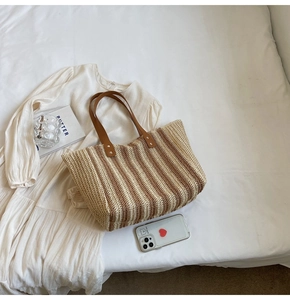 Détail du sac cabas en paille à rayures verticales avec anses en cuir marron et rivets