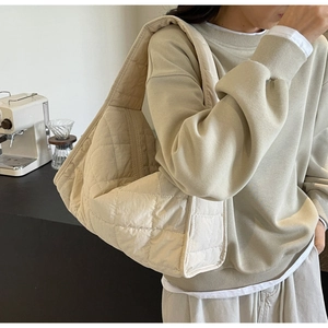 Detail of light beige quilted canvas tote bag showing the soft diamond pattern and texture