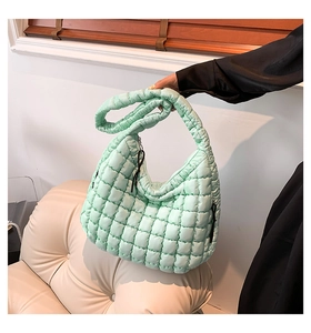 Detail of mint green quilted puffer shoulder bag in soft semi-glossy nylon material