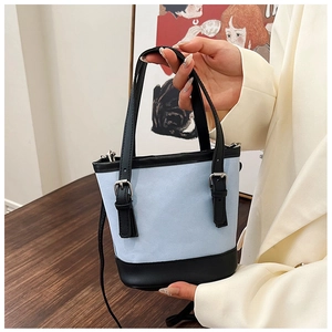 Detail shot of blue canvas and black leather colorblock bucket bag with silver metal buckles