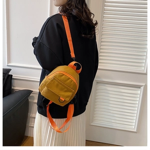 Détail d'un mini sac à dos en toile jaune gingembre avec fermetures éclair orange sur modèle