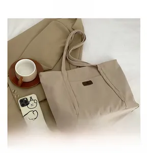Detailed close-up of a beige canvas tote bag with front pocket in a lifestyle setting