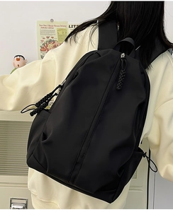 Close-up of minimalist black nylon backpack with a long braided cord zipper puller