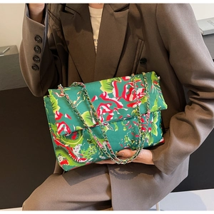 Detail shot of green floral canvas crossbody bag with silver chain strap on model