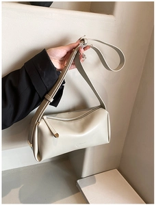 Detail view of cream white cylindrical PU bag featuring a golden teardrop zipper puller