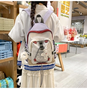 Detailed view of tricolor nylon backpack with cartoon UFO print and white pompom charm