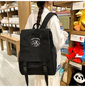 Detail of black nylon backpack with flip-top buckles and white cartoon UFO cat prints