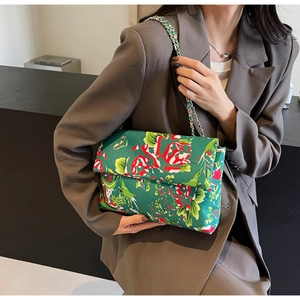 Detail of vibrant green floral canvas bag with metal chain strap on grey blazer