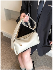 Detail view of cream PU leather cylinder shoulder bag with gold zipper and wide strap