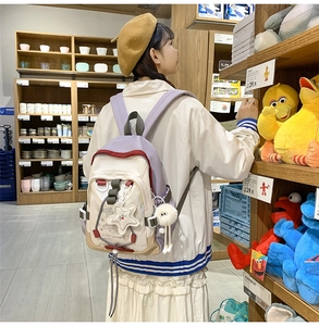 Detailed back view of a purple and beige nylon backpack with cute plush accessories