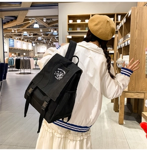 Detail view of black canvas backpack with dual buckle closure and white bell print details