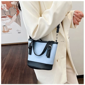 Detail of blue and black bucket bag with buckle design and adjustable leather strap