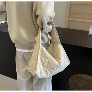 Detail view of cream quilted canvas tote bag with elegant rhombus stitching and zipper