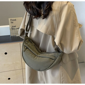 Olive green crescent crossbody bag shown on model with adjustable strap and zip closure