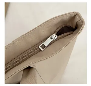 Detail view of smooth silver metal zipper and durable khaki canvas on minimalist tote bag