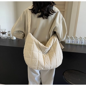 Detail of beige quilted canvas crossbody bag showing texture and wide shoulder strap