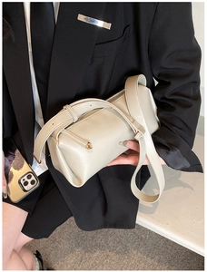 Detail shot of chic cream PU leather cylindrical bag with golden metal hardware and strap