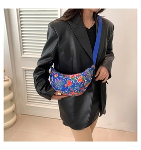 Blue floral crescent shoulder bag worn by model showing fit and patterned fabric detail