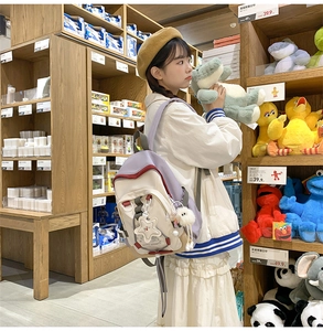 Detail of color-block nylon backpack with star and plush pendants in a shopping setting