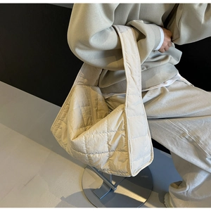 Detail of a large cream quilted tote bag showing the textured diamond stitch nylon fabric