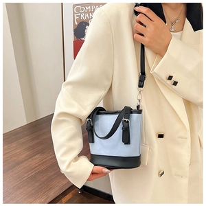 Detail of a stylish blue canvas bucket bag with black leather straps and adjustable belt