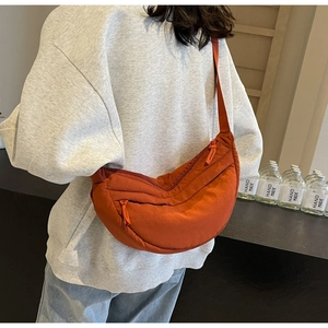 Detail view of brick red crescent nylon crossbody bag with adjustable strap for commuting