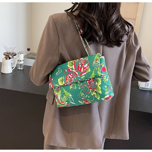 Detail of green floral canvas shoulder bag with rose prints and metal chain strap
