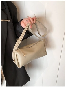 Detail view of cream-white cylinder shoulder bag with silver zipper and brand logo