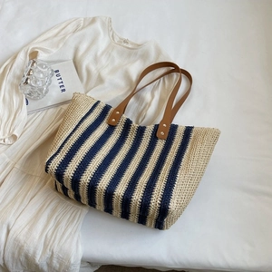 Sac fourre-tout rayé en paille avec anses en cuir marron sur fond de robe blanche