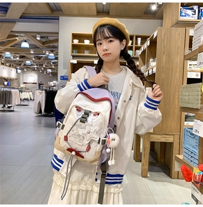 Close-up of stylish nylon backpack featuring cartoon UFO print and plush pendant