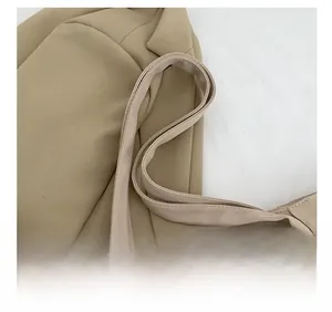 Detailed close-up of wide canvas shoulder strap with neat stitching on beige tote bag