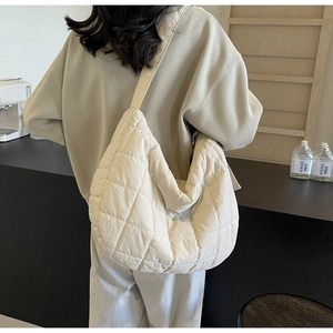 Close-up of beige quilted crossbody bag featuring soft crescent shape and nylon fabric