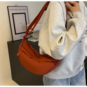 Model wearing orange crescent crossbody bag made of high-quality nylon fabric