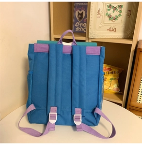 Detailed back view of a durable blue and purple nylon backpack with adjustable straps