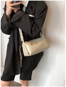 Detail shot of a minimalist cream PU leather baguette bag with embossed sun logo