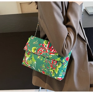 Detail of dragon pattern on silk shoulder bag with elegant silver chain strap