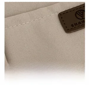 Detailed macro view of beige canvas fabric with high-quality stitching and a brown leather logo