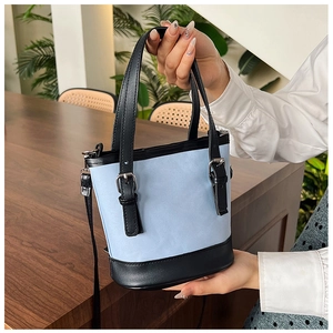 Detail view of light blue PU leather bucket bag with black handles and metal buckles