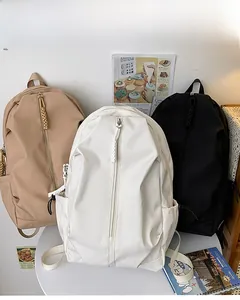 Close-up of three minimalist nylon backpacks in khaki, white and black colors on a table